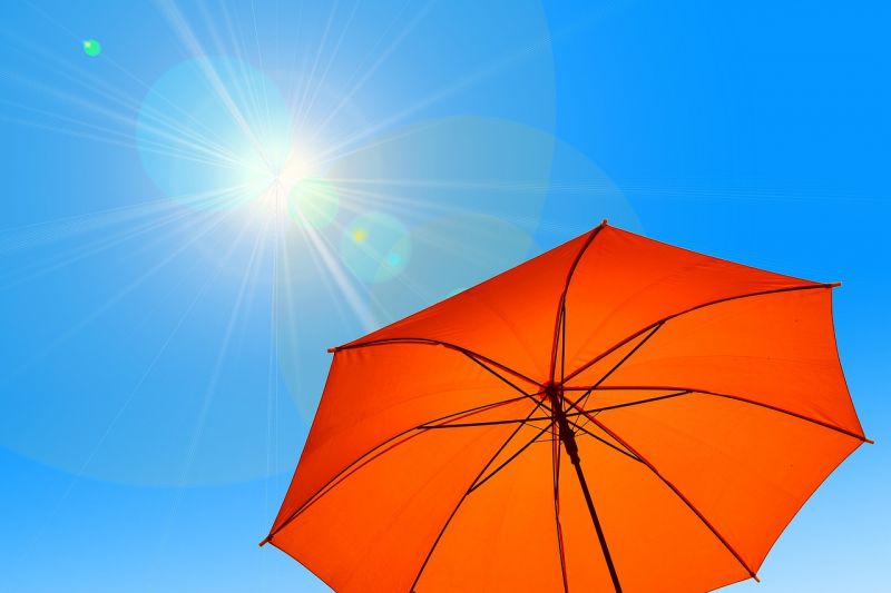 oranger Schirm vor wolkenlosem Himmel
