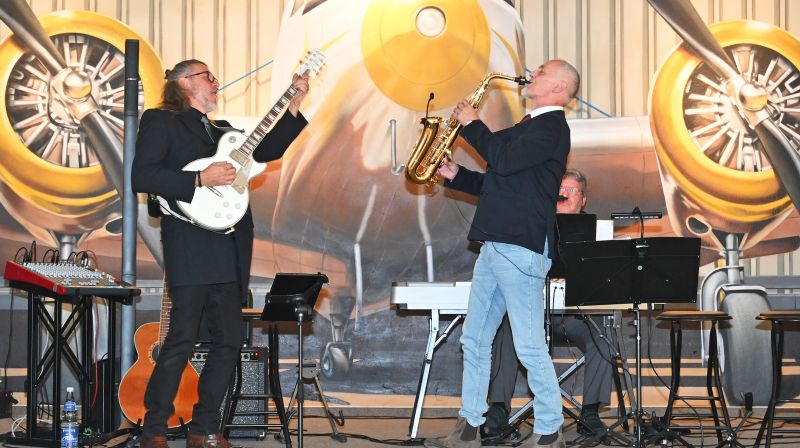 Der Saxophonist Matthias Wacker mit Gitarrist und Keyboarder musizieren auf der Bühne des Festsaals