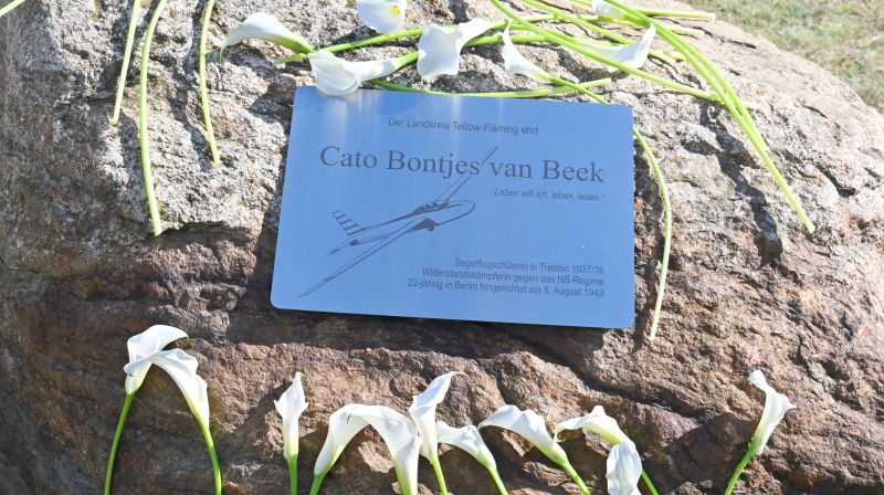Gedenkstein mit Andenkentafel an die Segelflugschülerin Cato Bontjes van Beek, niedergelegte weiße Callas