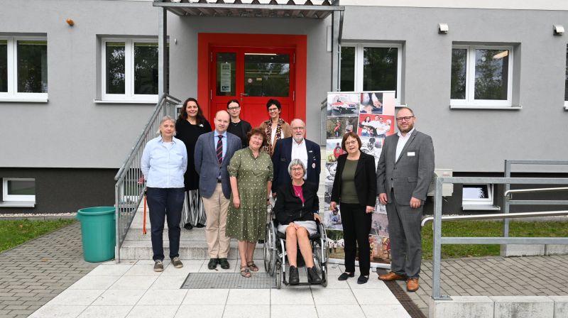 Personengruppe vor Eingang, Mitte Doris Lemmermeier (im Rollstuhl)