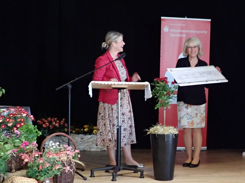 zwei Frauen, symbolischer Scheck, auf Bühne
