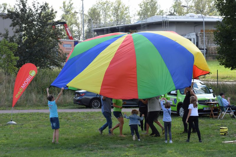 Kinder befördern gemeinsam buntes Tuch über ihre Köpfe