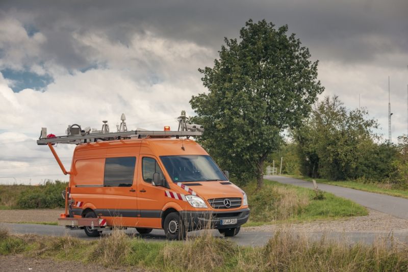 orangefarbener Transporter mit Messgeräten auf dem Dach